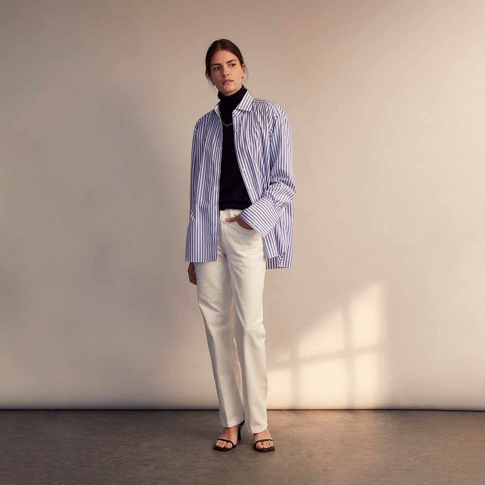 The Turnbull & Asser Pale Blue Candy Stripe Cotton Marlene Shirt is an oversized women's collared shirt with long sleeves, buttoned cuffs, and vertical blue and white stripes, shown laid flat on a white background.
