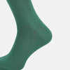 View 4 of product The Turnbull & Asser Forest Green/Navy Dot Mid-Length Sock is shown upright with the foot pointed right against a white background, highlighting its subtle polka dot pattern.