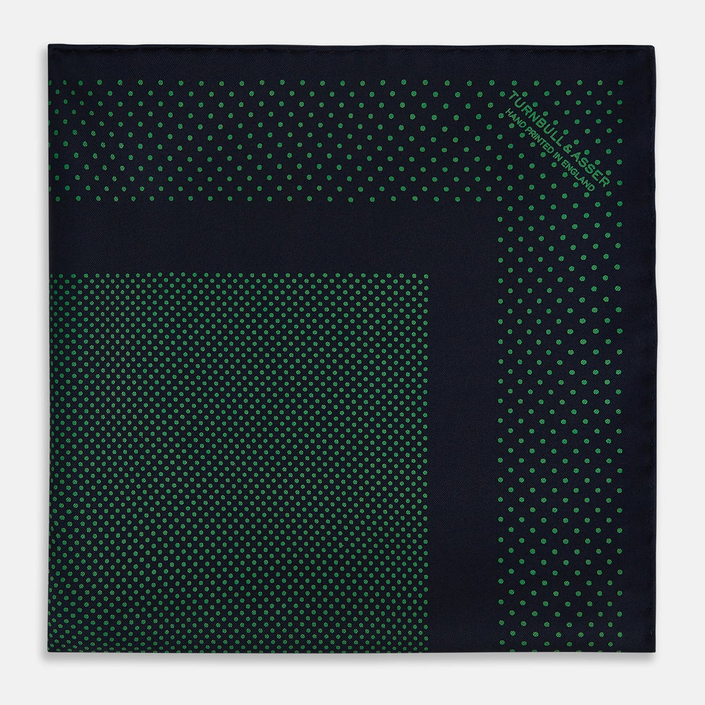 The Turnbull & Asser Navy and Green Dot Silk Pocket Square features dense green polka dots on navy silk, a solid navy border, and a band of spaced green dots—expertly handmade with precise finishing for an elegant look.