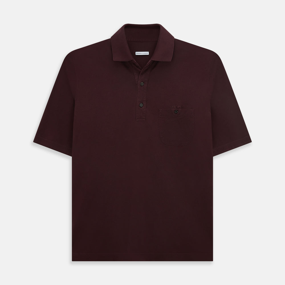 The Turnbull & Asser Burgundy Polo Shirt is crafted from soft cotton jersey with short sleeves, a classic collar, three front buttons, and a small buttoned chest pocket, shown flat on a white background.