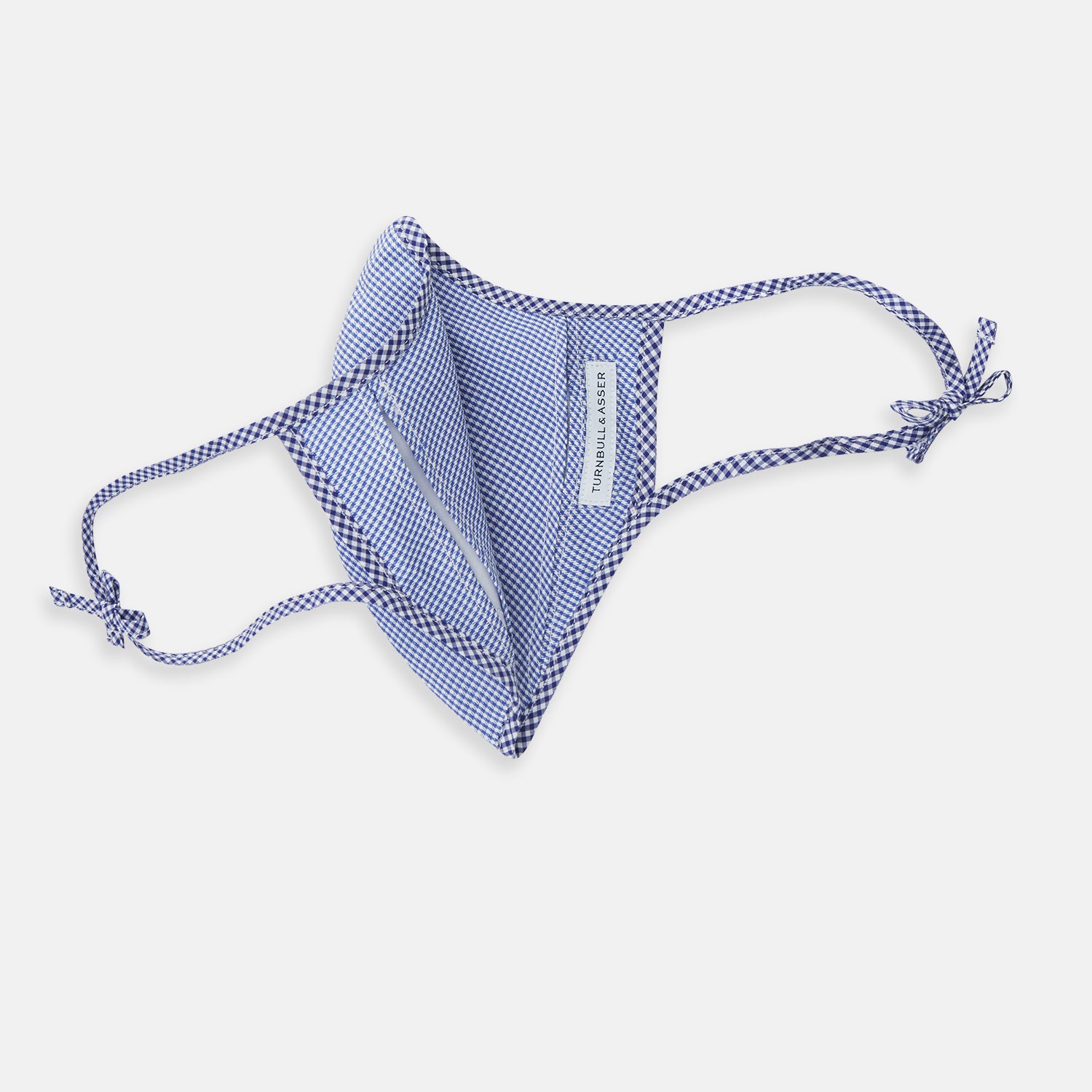 View 5 of product The Turnbull & Asser White & Navy Multi Check Commuter Mask comes with 3 Viroformula™ filters and two adjustable tie straps on each side, shown on a plain white background.