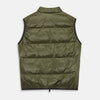 View 7 of product A man stands against a plain background wearing the Turnbull & Asser Green Peyton Sealup Quilted Gilet over a striped shirt, dark trousers, and white sneakers, with his hands in his pockets and looking slightly to the side.