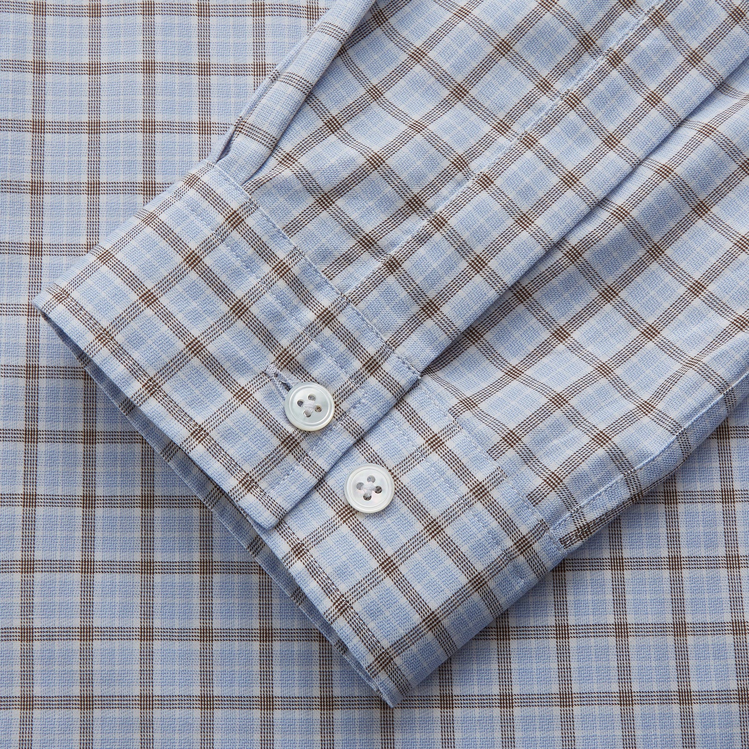 View 3 of product A man wearing glasses and a Pale Blue Multi Check Cashmerello Holiday Fit Winnington Shirt by Turnbull & Asser leans casually against a white countertop, looking at the camera with a neutral expression.