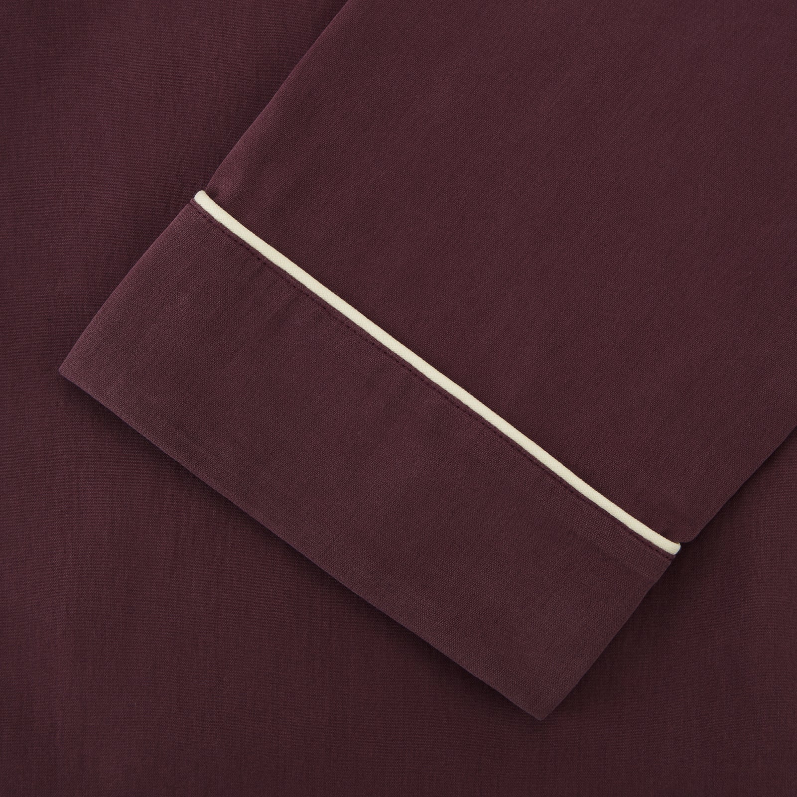 View 3 of product The Turnbull & Asser Plain Plum Silk Modern Pyjama Set, made in England, features white piping, a button-up long-sleeve top with three pockets, and matching pants. The pyjamas are shown against a white background.
