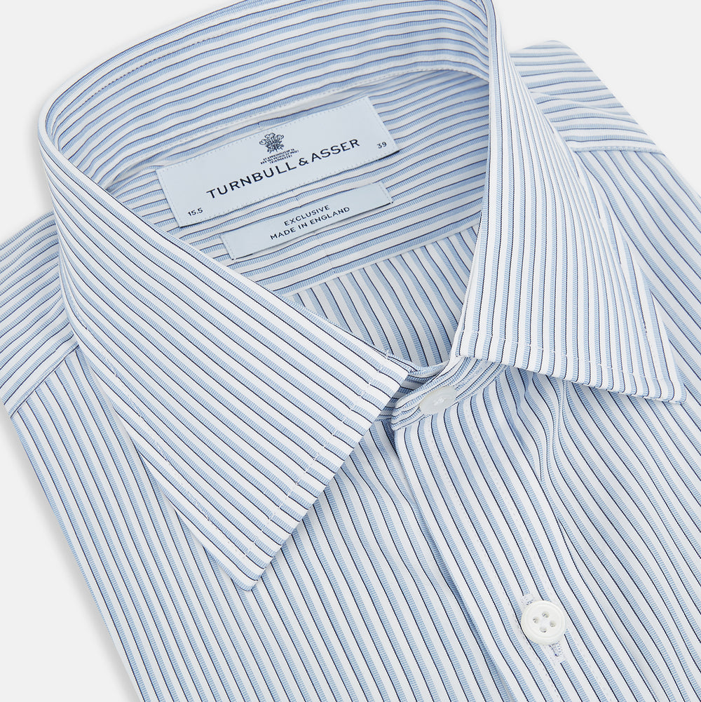 The Turnbull & Asser Sky Blue Shadow Pinstripe Mayfair Shirt, a long-sleeved, button-up shirt with a T&A collar and light blue and white thin vertical stripes, is displayed flat on a white background.