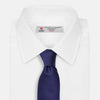 View 4 of product The PLAIN HERRINGBONE NAVY TIE by Turnbull & Asser, crafted from silk with a subtle pattern, is elegantly rolled and displayed against a plain white background.
