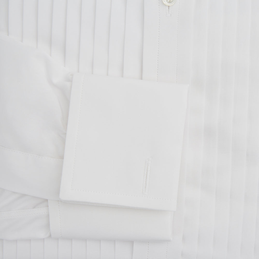 The Turnbull & Asser White Pleated Cotton Dress Shirt features a T&A collar, double cuffs, a button-down front, elegant chest pleats, and a slightly curved hem for a classic formal look.