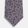 View 3 of product The Turnbull & Asser Purple and Blue Circle Ash Silk Tie features small blue, pink, and white circles on a dark purple background, adding an elegant touch when displayed on a light surface.