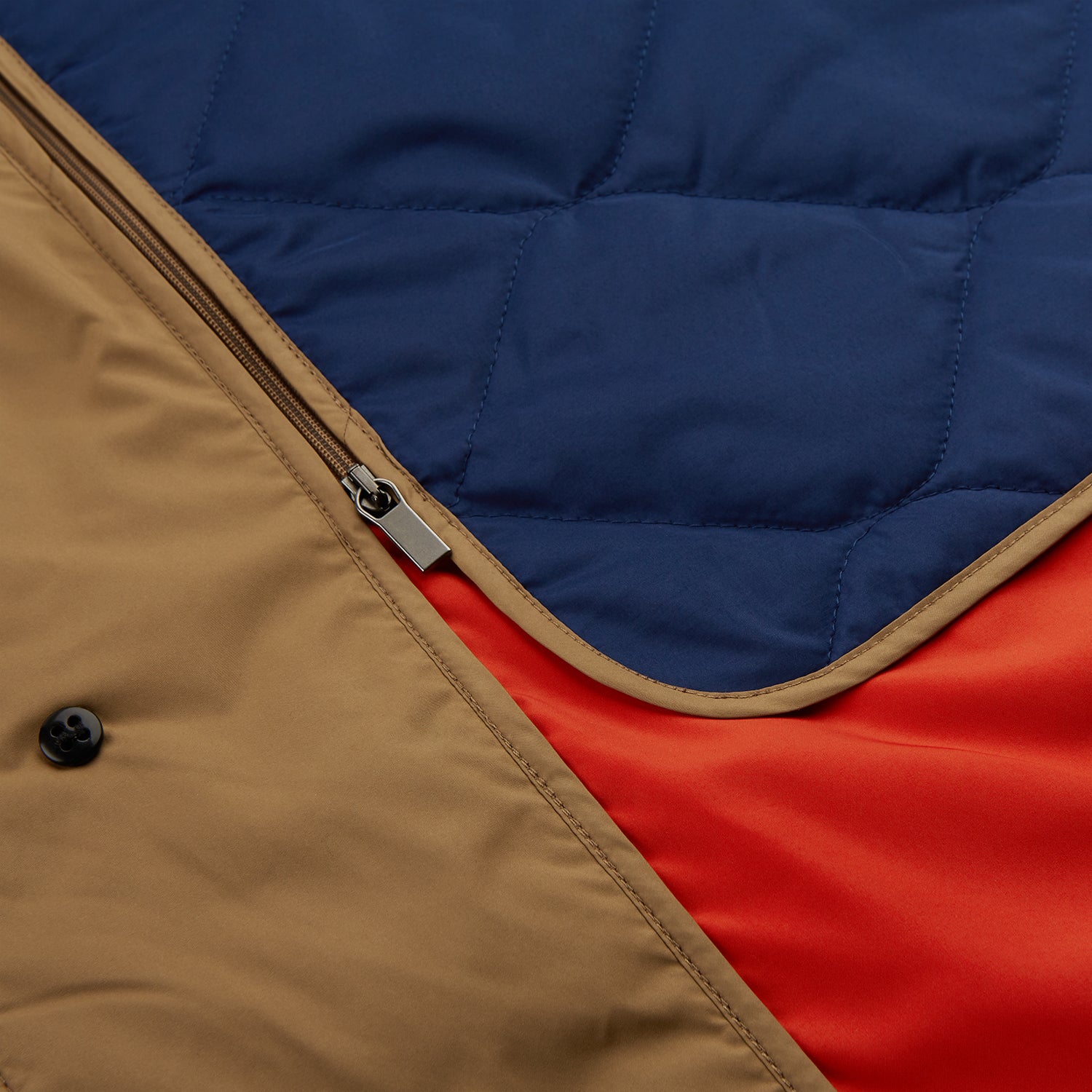 View 8 of product A person wears the Turnbull & Asser Camel Quintern Sealup Raincoat with Detachable Liner, paired with dark pants, standing against a plain light gray background, showing the sleek technical rainwear style with one hand in a pocket.