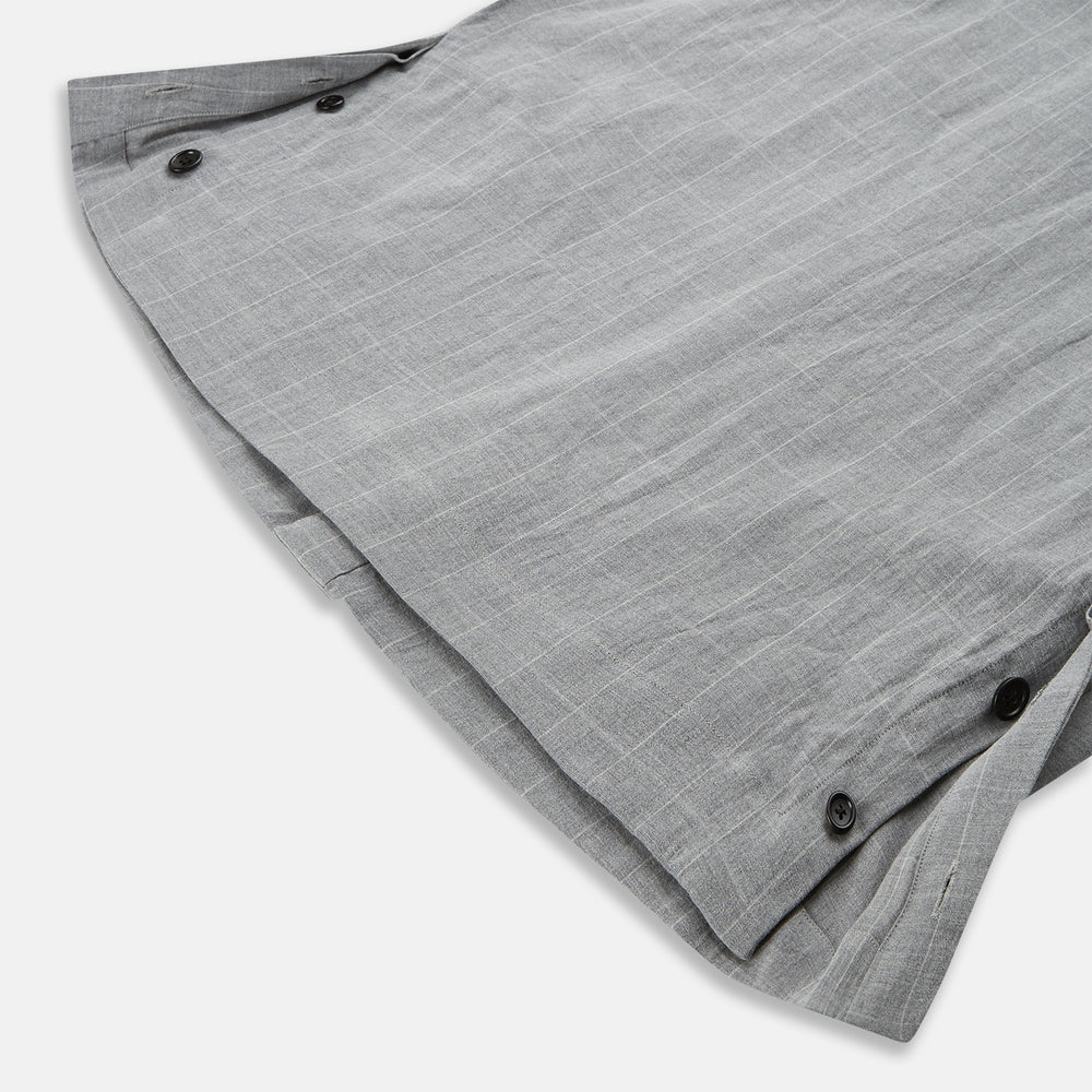 The Turnbull & Asser Grey Check Hampstead Overshirt features a light gray check pattern, pointed collar, chest pocket, and two zippered side pockets, displayed flat against a white background.