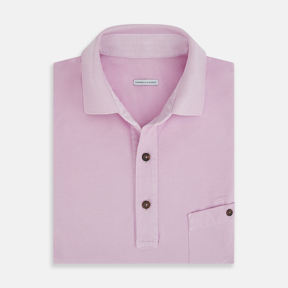 The Turnbull & Asser Pink Polo Shirt is a men's cotton polo with short sleeves, a collar, three dark buttons, and a chest pocket with a button, shown laid flat on a white background.