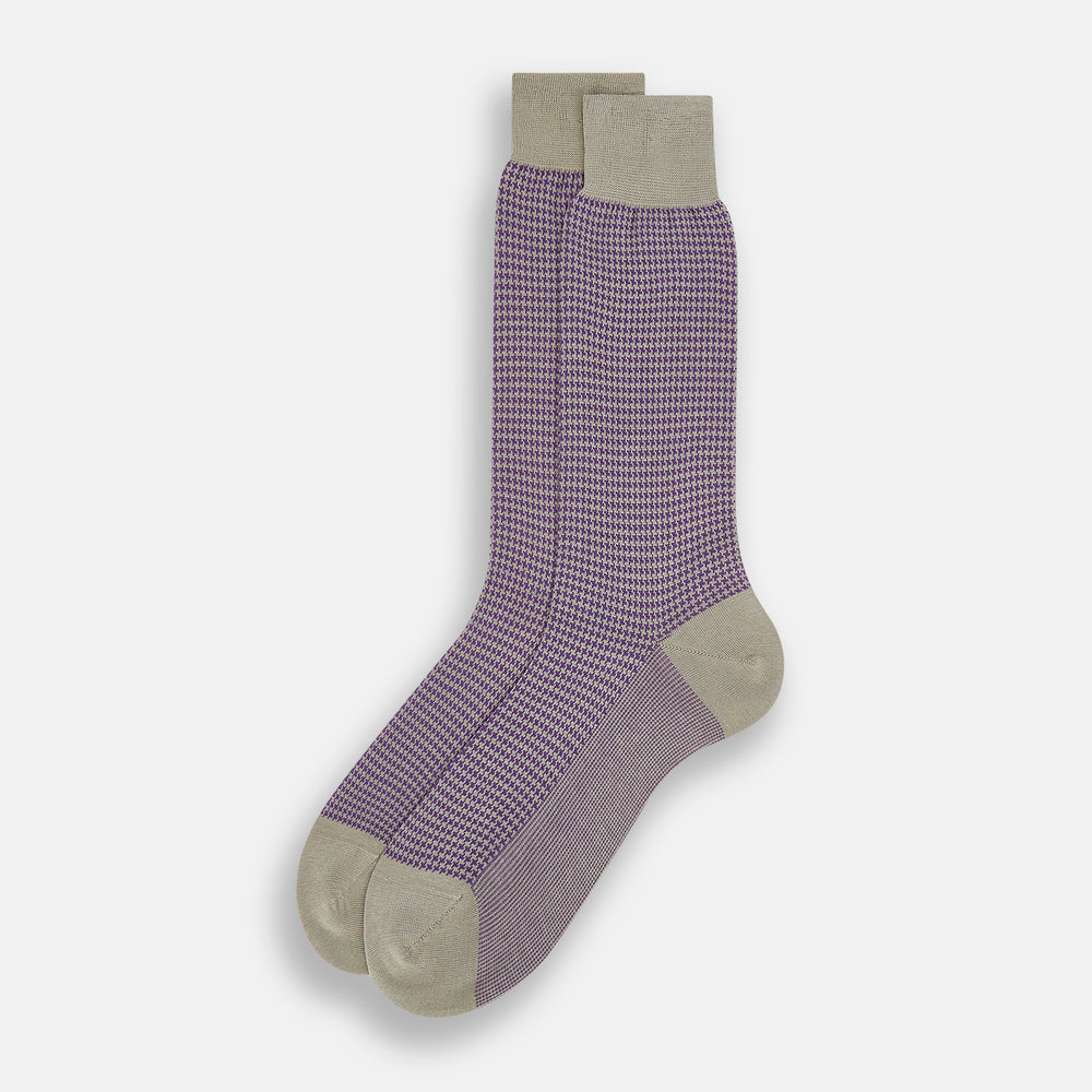 The Turnbull & Asser Concrete Houndstooth Mid-Length Sock features a purple and black houndstooth pattern with beige cuff, heel, and toe, crafted from soft cotton and shown on a plain white background.