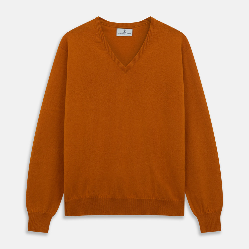 The Turnbull & Asser Rust Paden V-Neck Jumper, a pure cashmere sweater with long sleeves and ribbed cuffs and hem, is laid flat on a white background with the label visible at the neck.