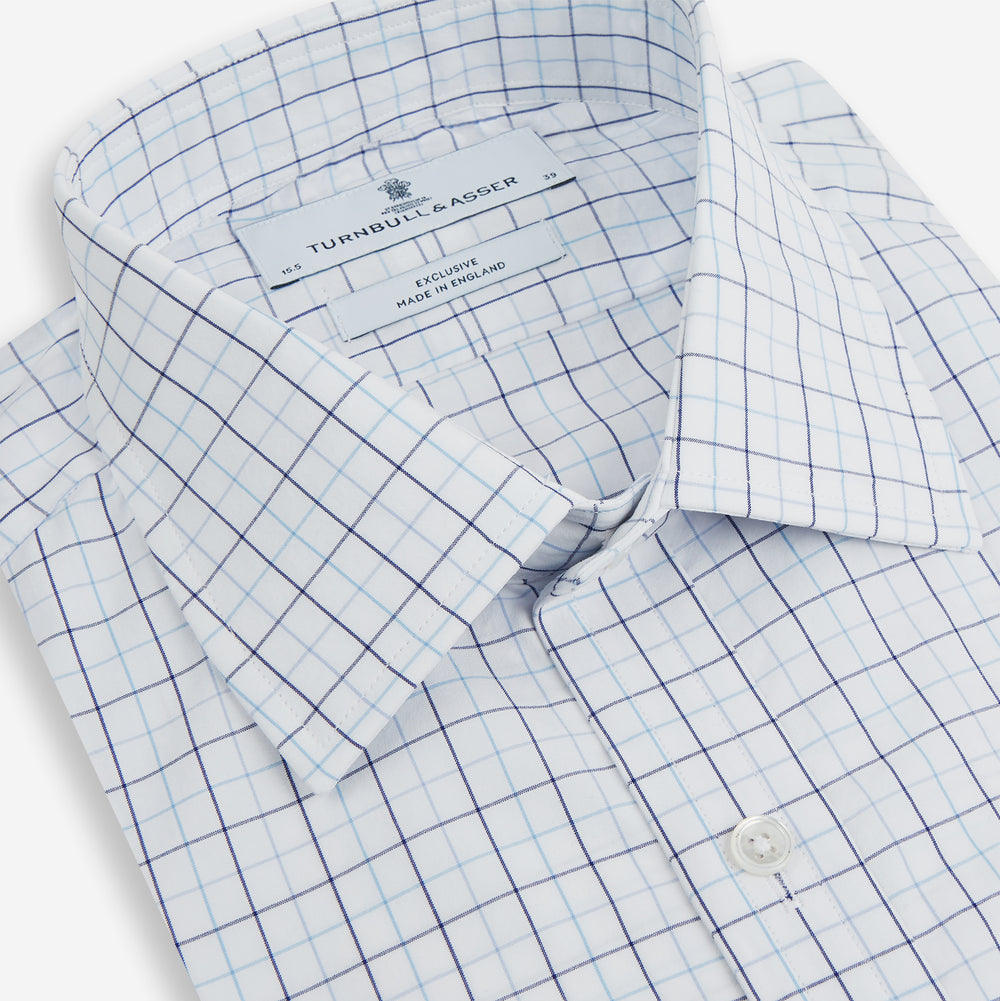 The Blue Overlay Grid Check Mayfair Shirt by Turnbull & Asser features a light blue and white grid check pattern with long sleeves and button-up design, making it a versatile wardrobe staple. Displayed on a plain white background.