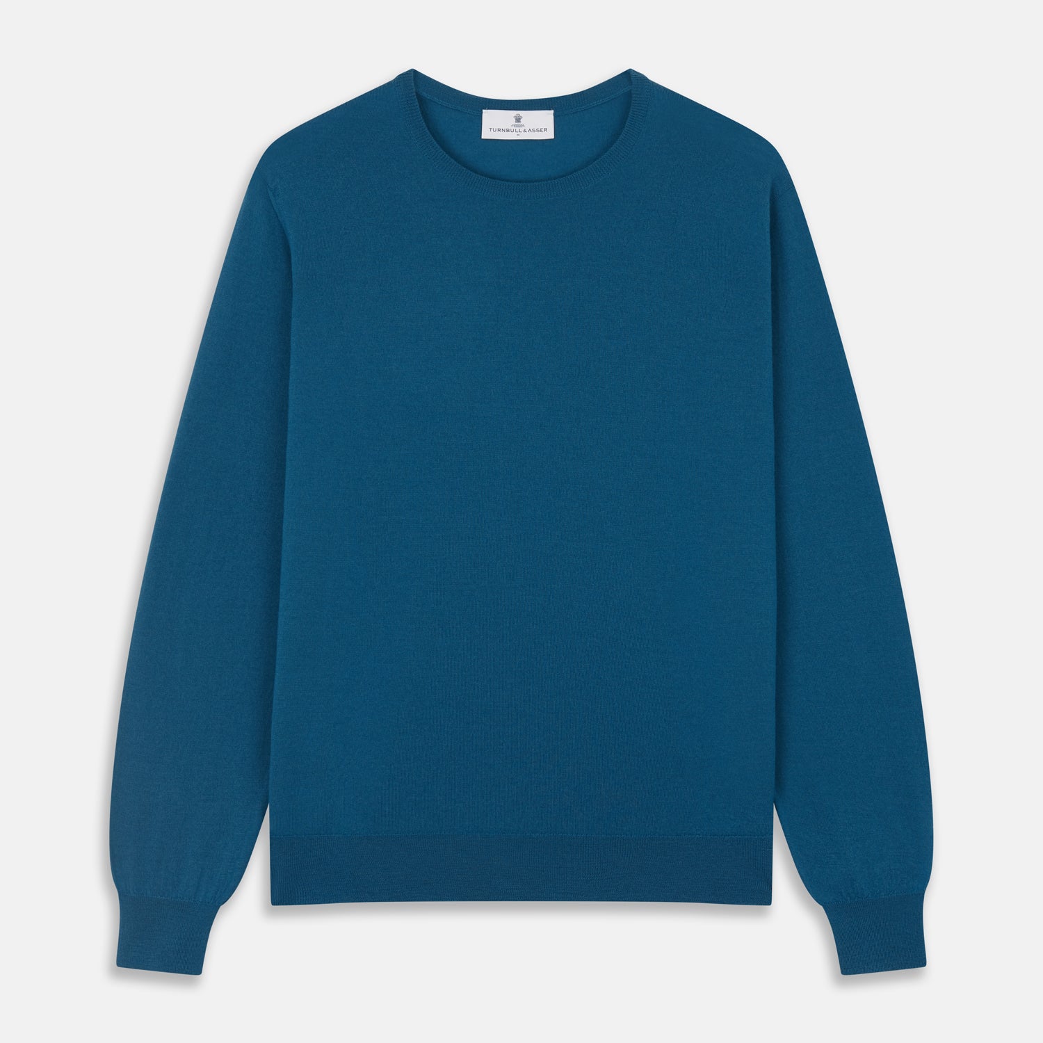 View 2 of product A man with light skin and short brown hair stands against a plain background, wearing the Turnbull & Asser Ocean Blue Merino Kingston Crew Neck Jumper and cream-colored pants, looking directly at the camera with a neutral expression.
