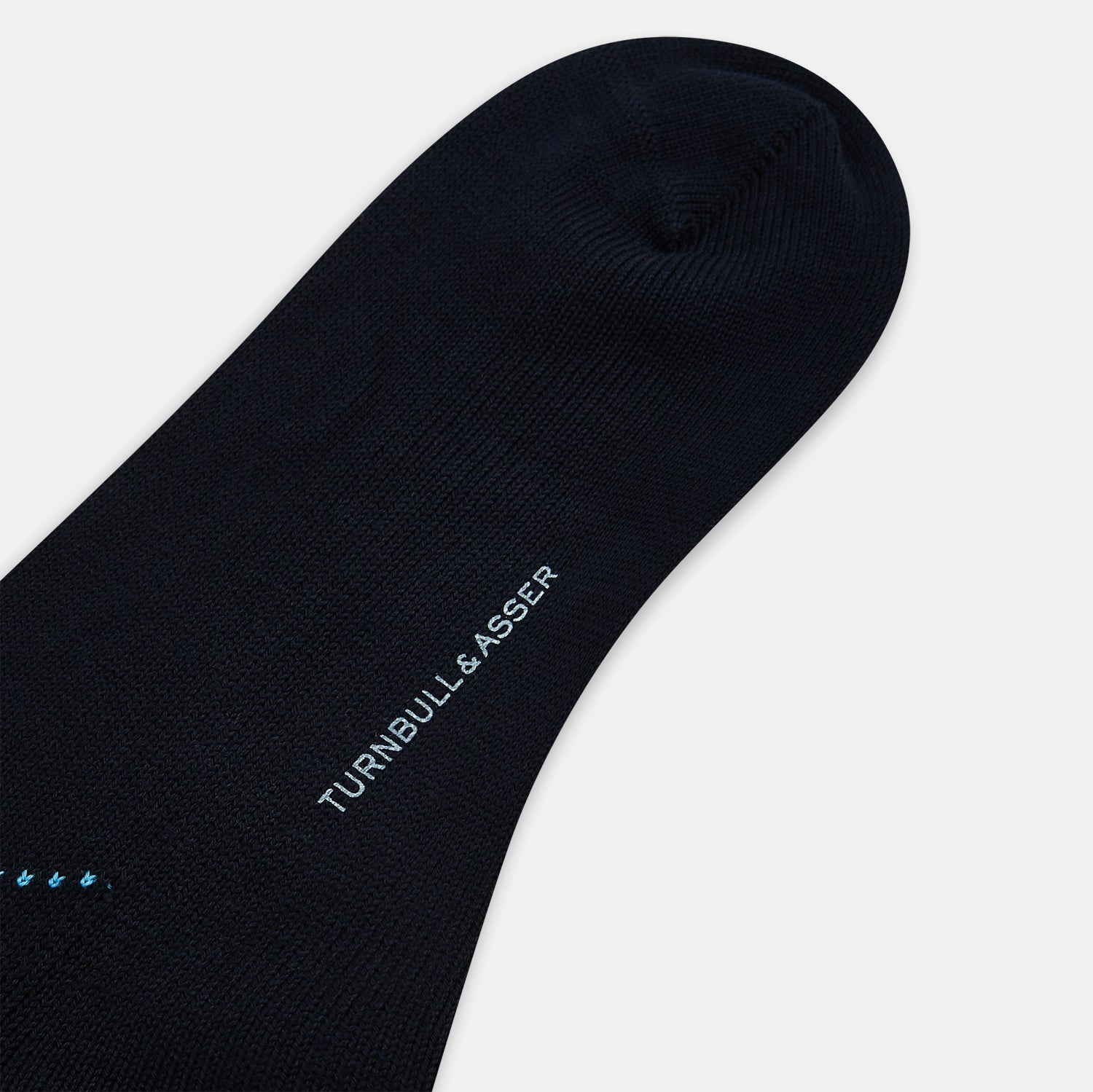 View 3 of product The Turnbull & Asser Navy Check Mid-Length Sock, crafted from ultra-soft cotton, features a blue and light blue argyle pattern with diamond shapes and dotted lines, and is showcased against a plain white background.