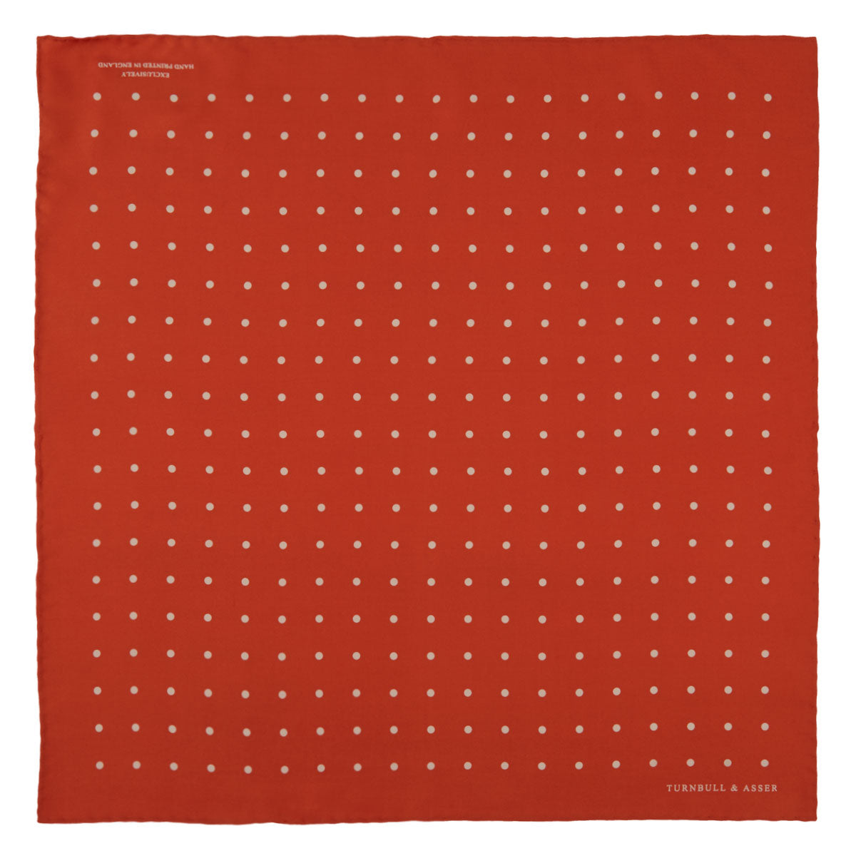 View 2 of product The Orange Spot Silk Pocket Square by Turnbull & Asser features evenly spaced white polka dots and the brand’s name in one corner, making this dapper accessory a standout addition to any outfit.