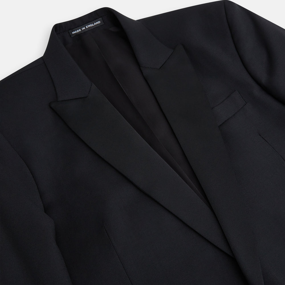 The Turnbull & Asser Black Single Breasted Dinner Suit features fine wool, a satin shawl collar jacket, and matching trousers—perfect formal wear, shown on a plain white background.