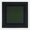 View 4 of product The Turnbull & Asser Navy and Kelly Green Dot Silk Pocket Square features small green dots on navy silk and a folded corner displaying the reverse—an elegant, handmade accessory perfect for enhancing any formal attire.