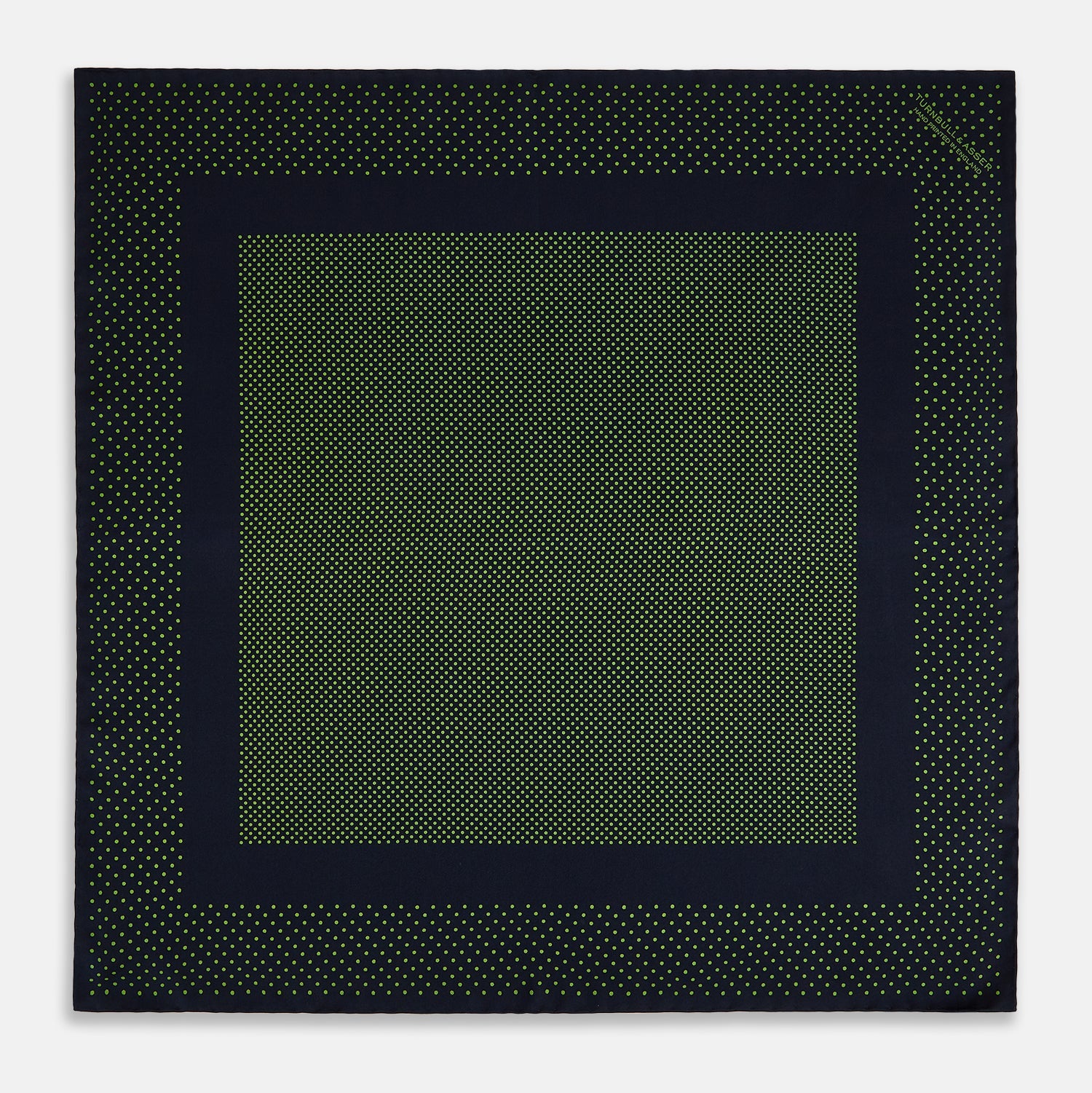 View 4 of product The Turnbull & Asser Navy and Kelly Green Dot Silk Pocket Square features small green dots on navy silk and a folded corner displaying the reverse—an elegant, handmade accessory perfect for enhancing any formal attire.