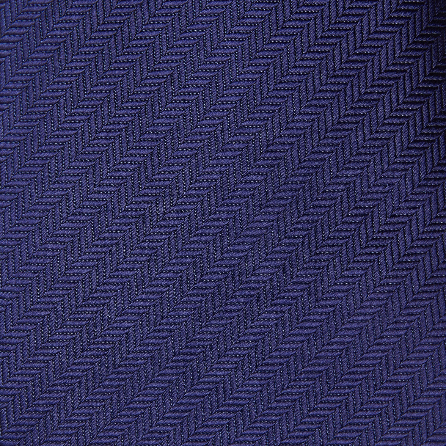 View 2 of product The PLAIN HERRINGBONE NAVY TIE by Turnbull & Asser, crafted from silk with a subtle pattern, is elegantly rolled and displayed against a plain white background.