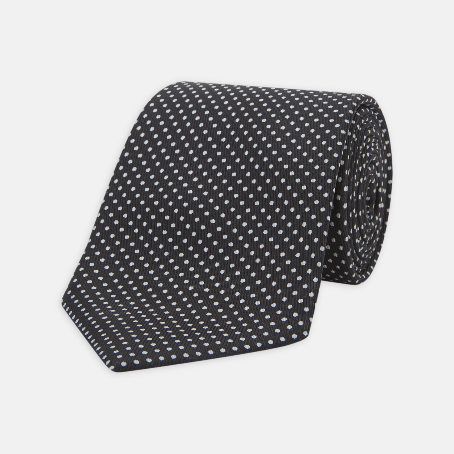 View 1 of product The Turnbull & Asser Black and White Spot Printed Silk Tie, shown neatly rolled on a plain white background, is an essential accessory to elevate any smart attire.