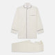 The Cream Pattern Cotton Blend Quin Pyjama Set by Turnbull & Asser features cream stripes, a long-sleeve button-up camp collar shirt with a chest pocket and black piping, and matching drawstring pants.