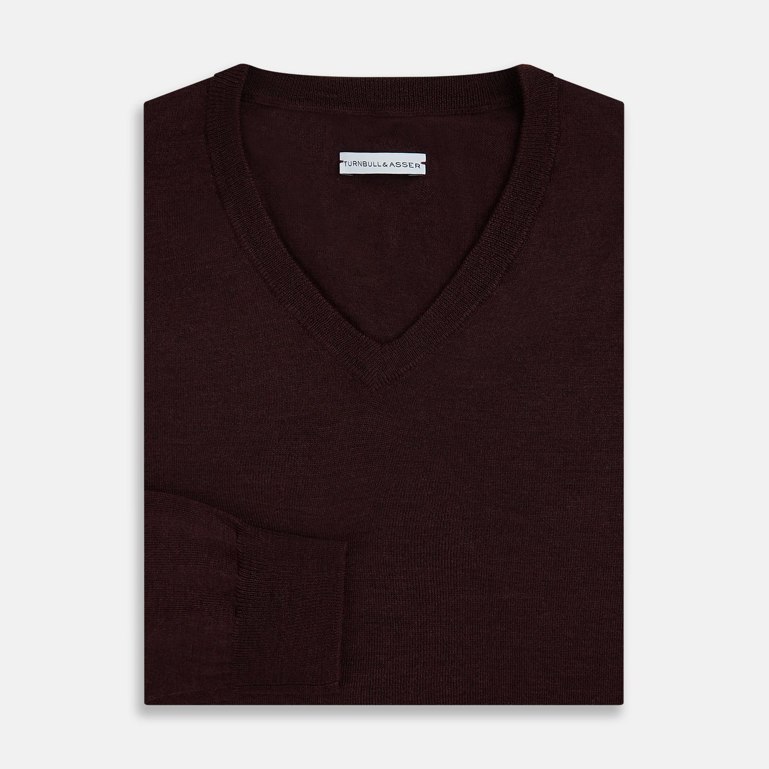 View 7 of product The Turnbull & Asser Burgundy Fine Merino V-Neck Jumper features a classic plain knit design with long sleeves, showcased against a crisp white background.