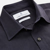 View 5 of product A man stands against a beige background wearing the Turnbull & Asser Navy Weekend Fit Cotton & Wool Shirt with a Derby collar and 1 button cuffs, paired with brown pants and black shoes, looking to the side with a neutral expression.