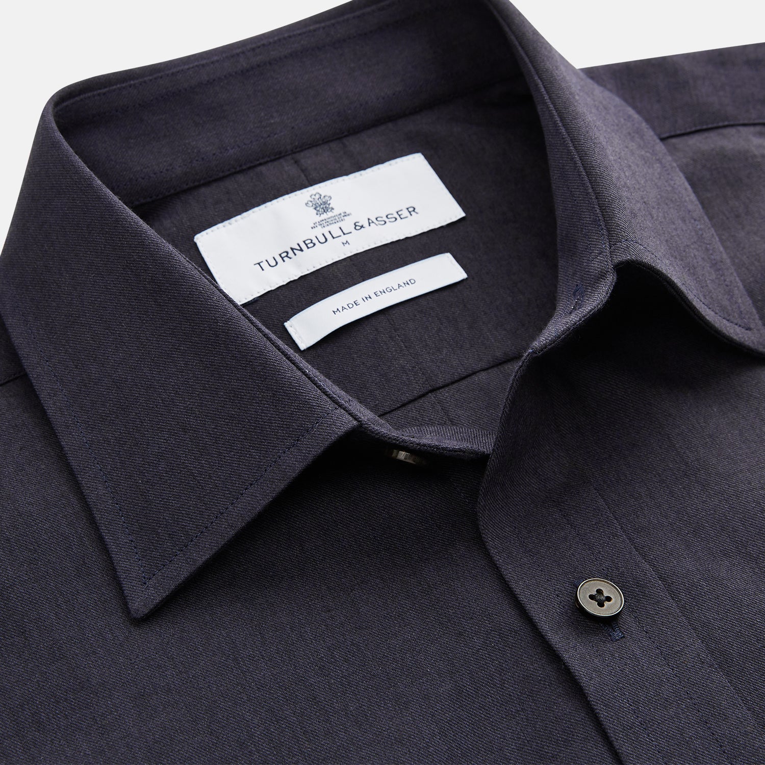 View 5 of product A man stands against a beige background wearing the Turnbull & Asser Navy Weekend Fit Cotton & Wool Shirt with a Derby collar and 1 button cuffs, paired with brown pants and black shoes, looking to the side with a neutral expression.