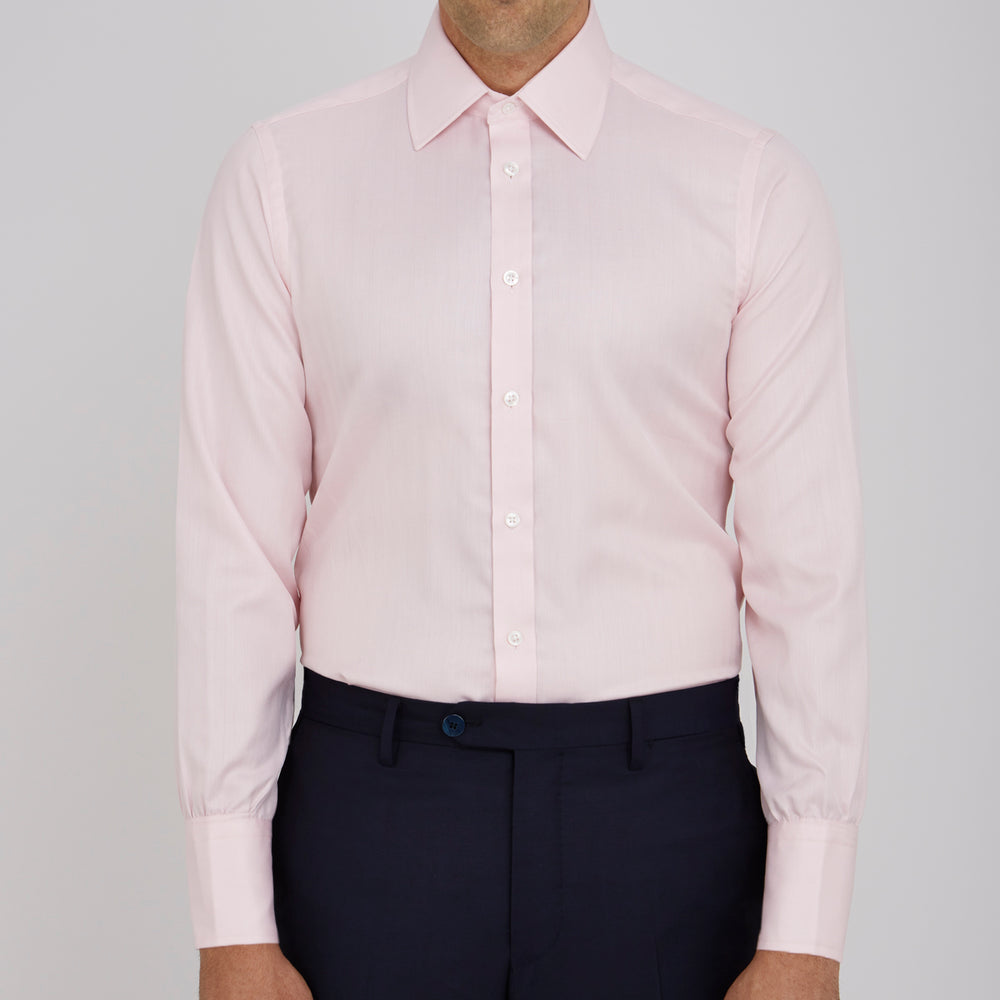 A Pink Herringbone Superfine Cotton Shirt by Turnbull & Asser, featuring a T&A collar and 3-button cuffs, is neatly folded with the inner collar label visible and white buttons, set against a plain white background.