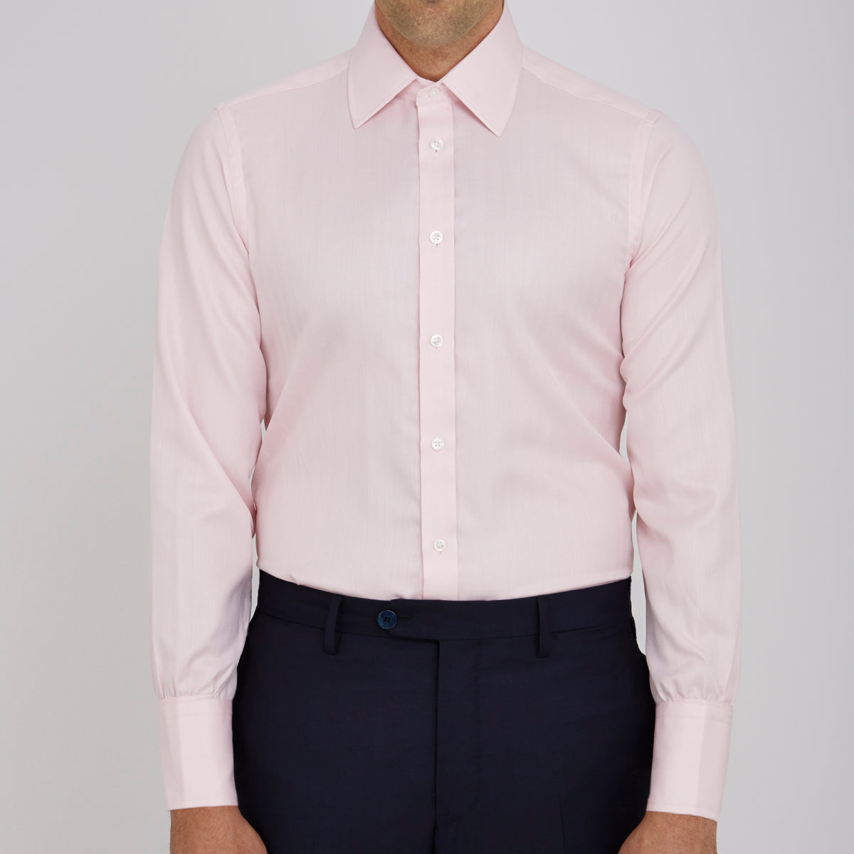 View 2 of product A Pink Herringbone Superfine Cotton Shirt by Turnbull & Asser, featuring a T&A collar and 3-button cuffs, is neatly folded with the inner collar label visible and white buttons, set against a plain white background.