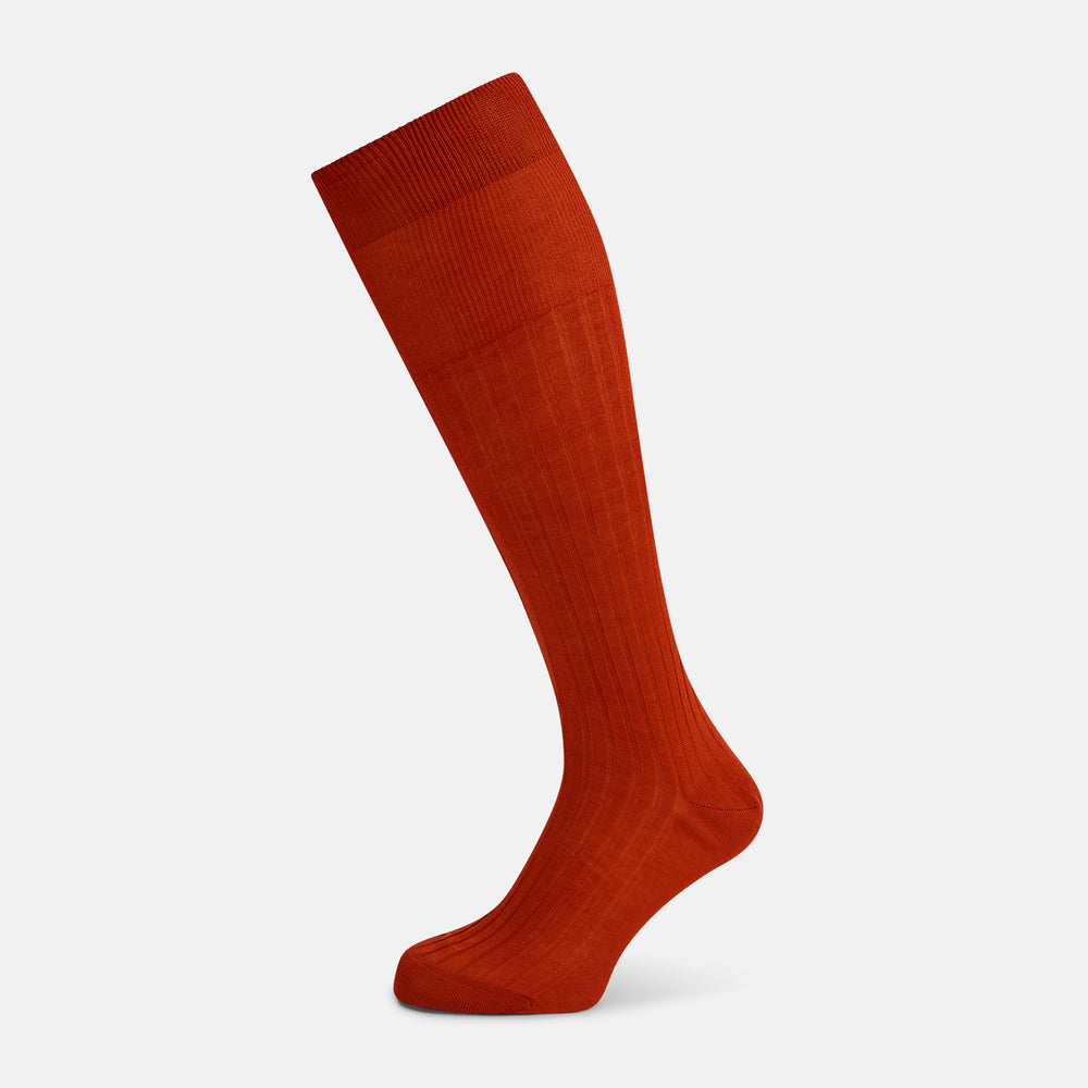 A single Rust Long Sock by Turnbull & Asser, knee-high and ribbed, made from mercerised Egyptian cotton, is shown at a side angle against a plain white background with the foot pointing slightly downward.