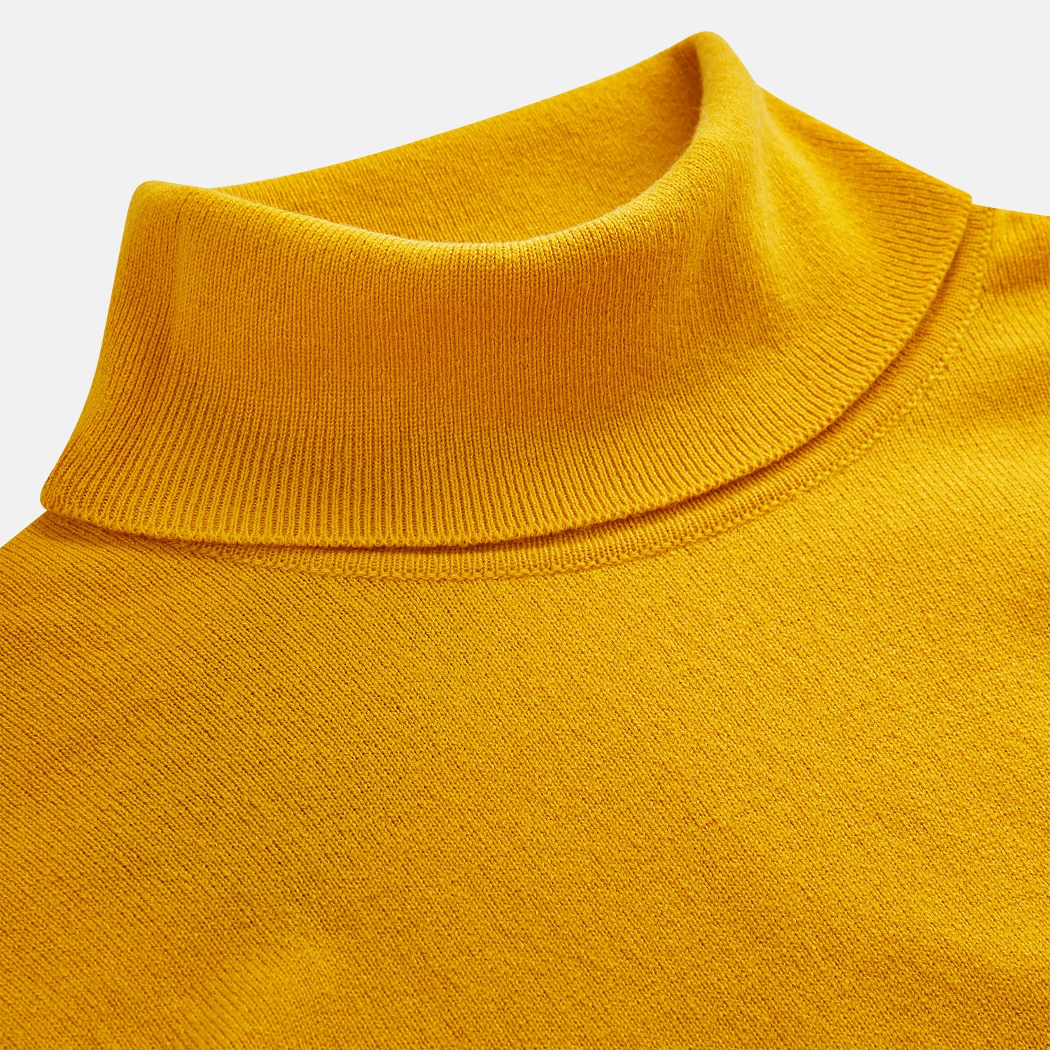 View 3 of product A man with short hair and a beard wears the Gold Aubrey Cashmere Roll Neck Jumper by Turnbull & Asser with dark pants, standing against a plain beige background and calmly looking at the camera, highlighting this stylish autumn sweater look.