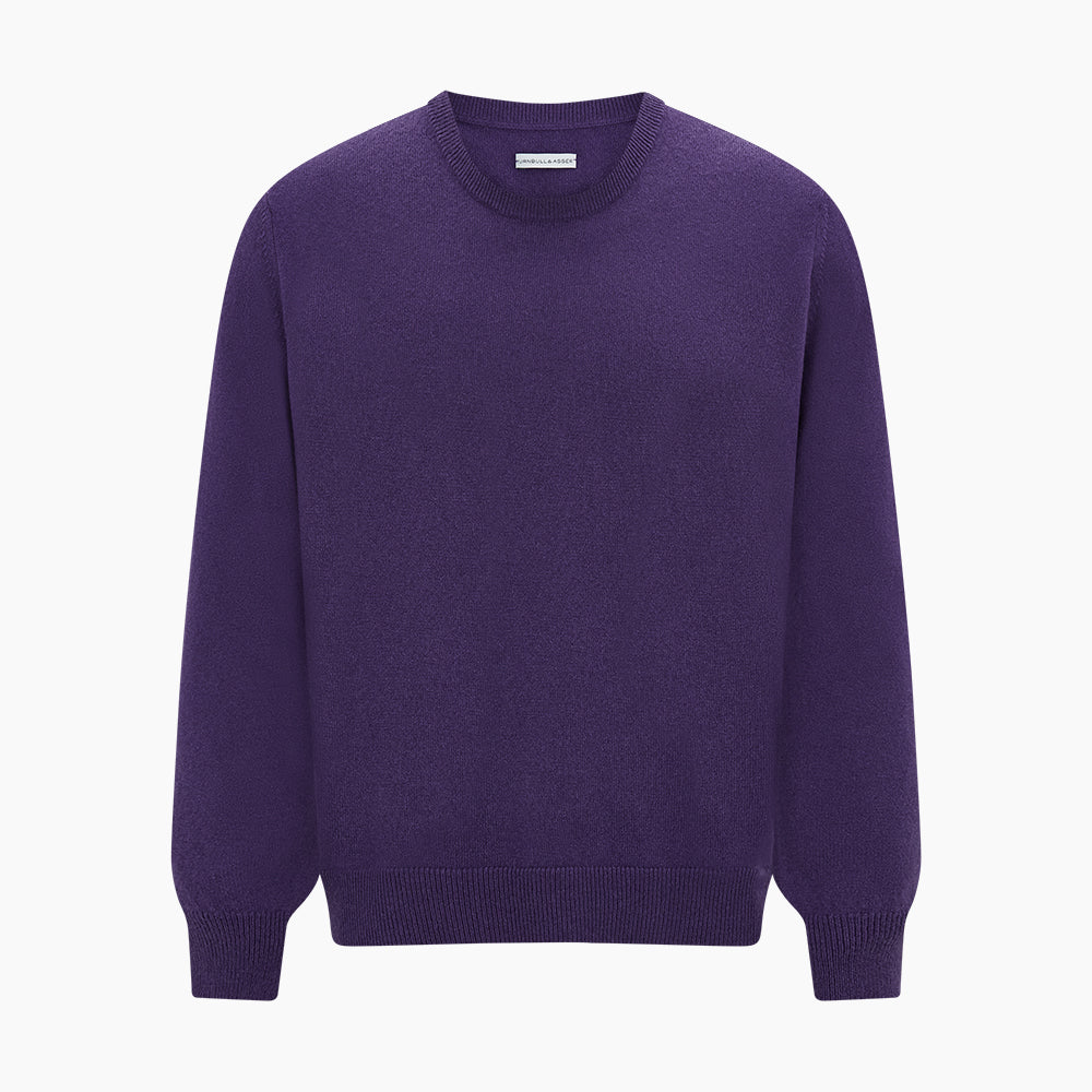 The Turnbull & Asser Purple Cashmere Round Neck Jumper features long sleeves, ribbed cuffs, hem, and collar for an elegant silhouette. This versatile knitwear piece is shown against a white background.