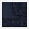 View 1 of product The Turnbull & Asser Midnight Blue Dot Silk Pocket Square features a neatly folded, handmade design with small light blue polka dots and a plain border.