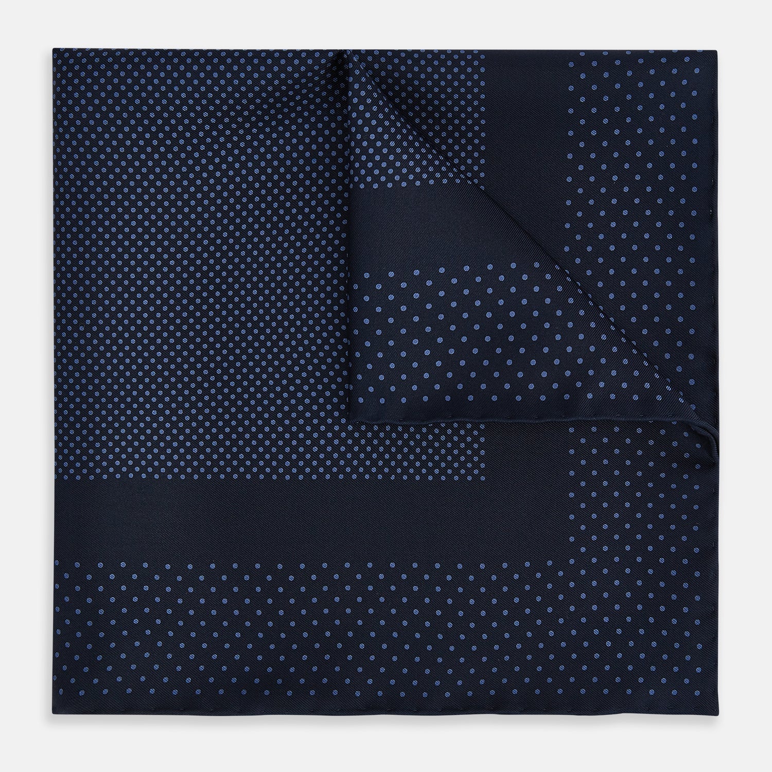 View 1 of product The Turnbull & Asser Midnight Blue Dot Silk Pocket Square features a neatly folded, handmade design with small light blue polka dots and a plain border.