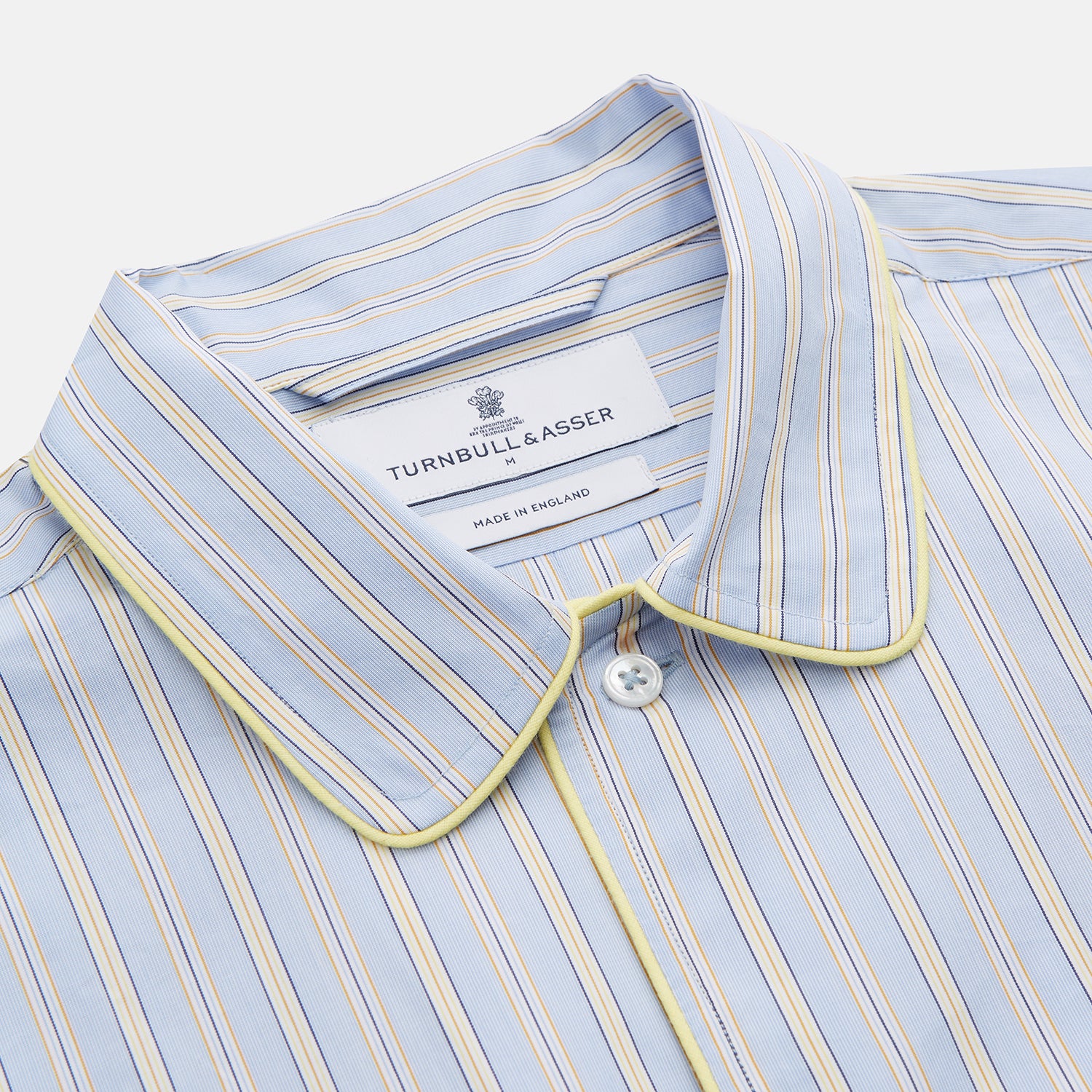 View 2 of product The Turnbull & Asser Blue and Yellow Stripe Poplin Cotton Nightshirt features light blue and yellow vertical stripes, long sleeves, a classic collar, single chest pocket, rounded hem, and is displayed flat on a white background.