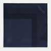 View 3 of product The Turnbull & Asser Midnight Blue Dot Silk Pocket Square features a neatly folded, handmade design with small light blue polka dots and a plain border.