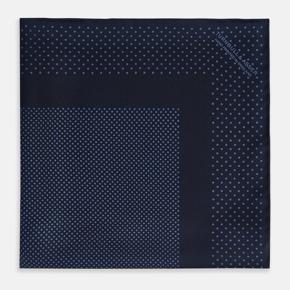 The Turnbull & Asser Midnight Blue Dot Silk Pocket Square features a neatly folded, handmade design with small light blue polka dots and a plain border.