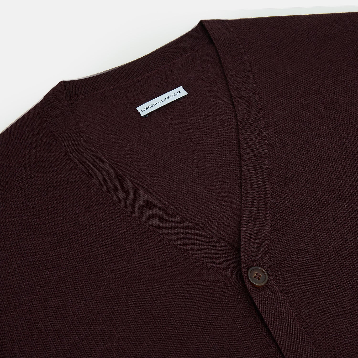 View 2 of product The Turnbull & Asser Burgundy Fine Merino V-Neck Cardigan features long sleeves and a button-down front, highlighting elegant handcrafted knitwear against a plain white background.