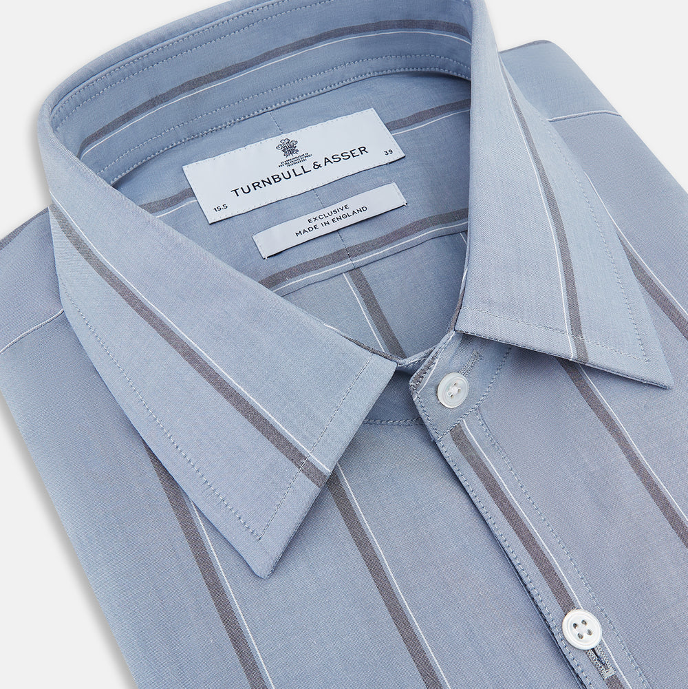 The Steel Blue Track Stripe Westminster Shirt by Turnbull & Asser features dark pinstripes, a classic collar, white buttons, and buttoned cuffs—expertly crafted to highlight British craftsmanship. Laid flat on white background.