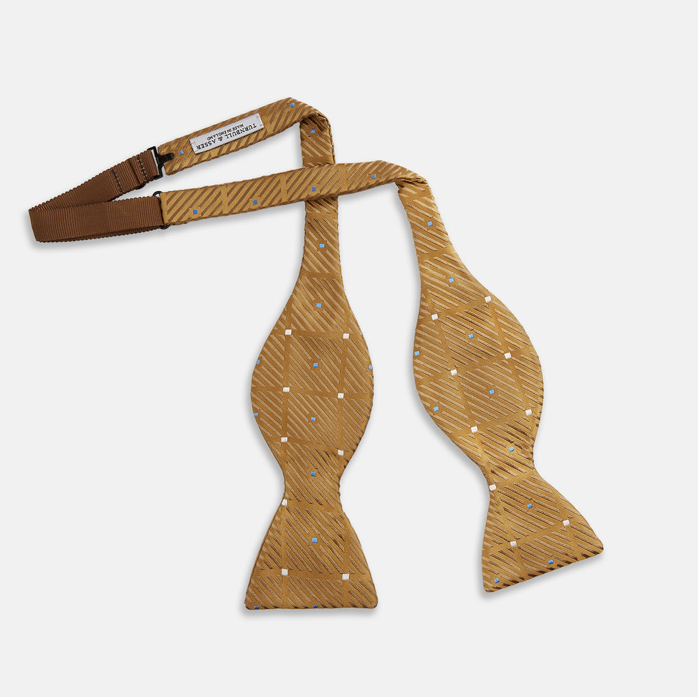 The Thistle Petersham Double End Bow Tie by Turnbull & Asser features a golden brown hue with a subtle diagonal stripe and blue and white square accents—an elegant accessory, pictured on a plain white background.