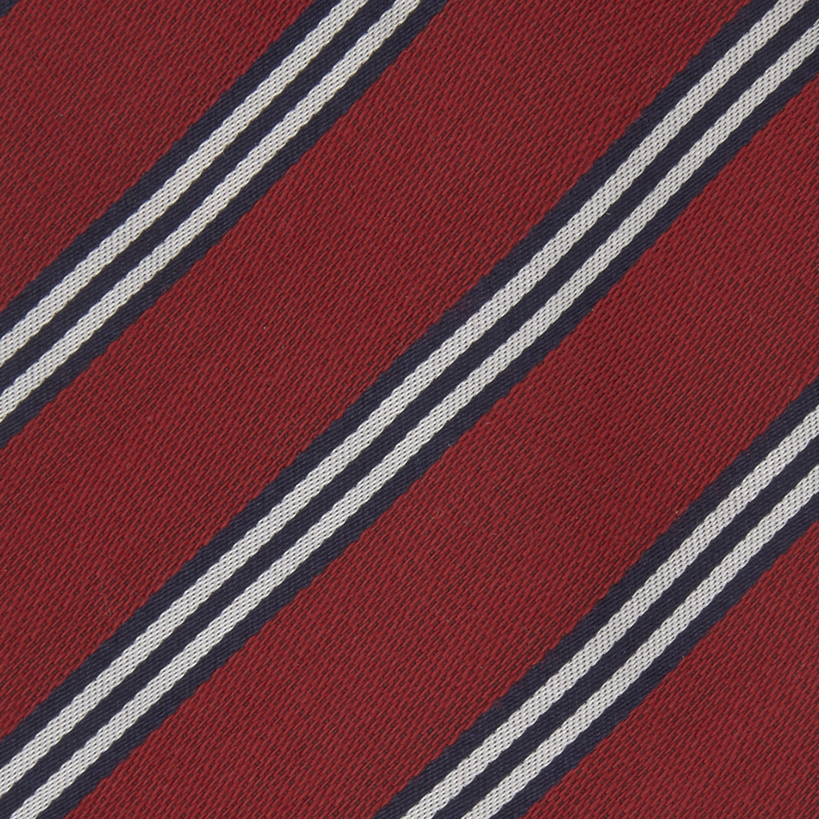 View 3 of product The Turnbull & Asser GGT92000 3042 48 OS is a rolled-up red cotton silk stripe tie with diagonal white and navy blue stripes, displayed on a plain white background.