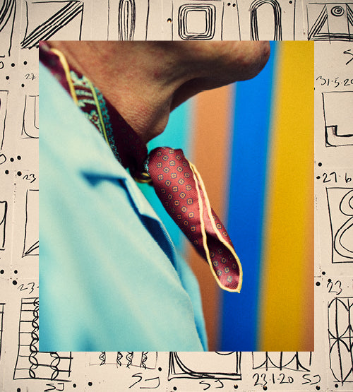 Close-up of a person’s neck wearing a blue shirt and a red patterned necktie, with a colorful striped background and a white border featuring abstract black line drawings and numbers.