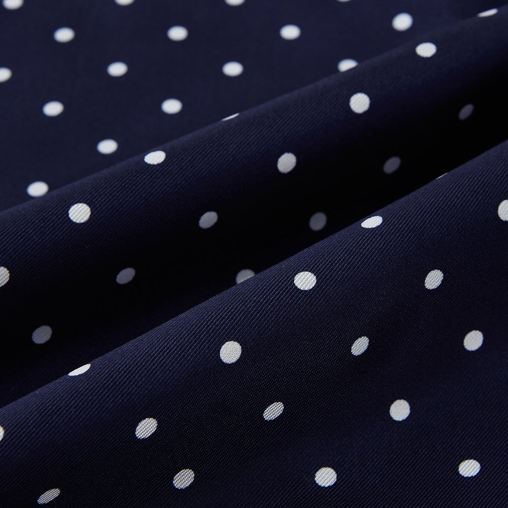 The Navy and White Spotted Silk Scarf by Turnbull & Asser features white polka dots, a fringed edge, and the brand's name printed near the bottom on both sides. It is neatly folded at the top.