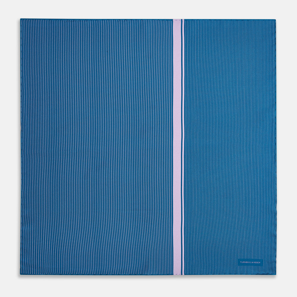 The Turnbull & Asser Blue and Lilac Stripe Silk Pocket Square features blue silk with white pinstripes, a bold lilac stripe near the edge, a turned-up corner revealing the reverse, and the brand name displayed in the bottom right.