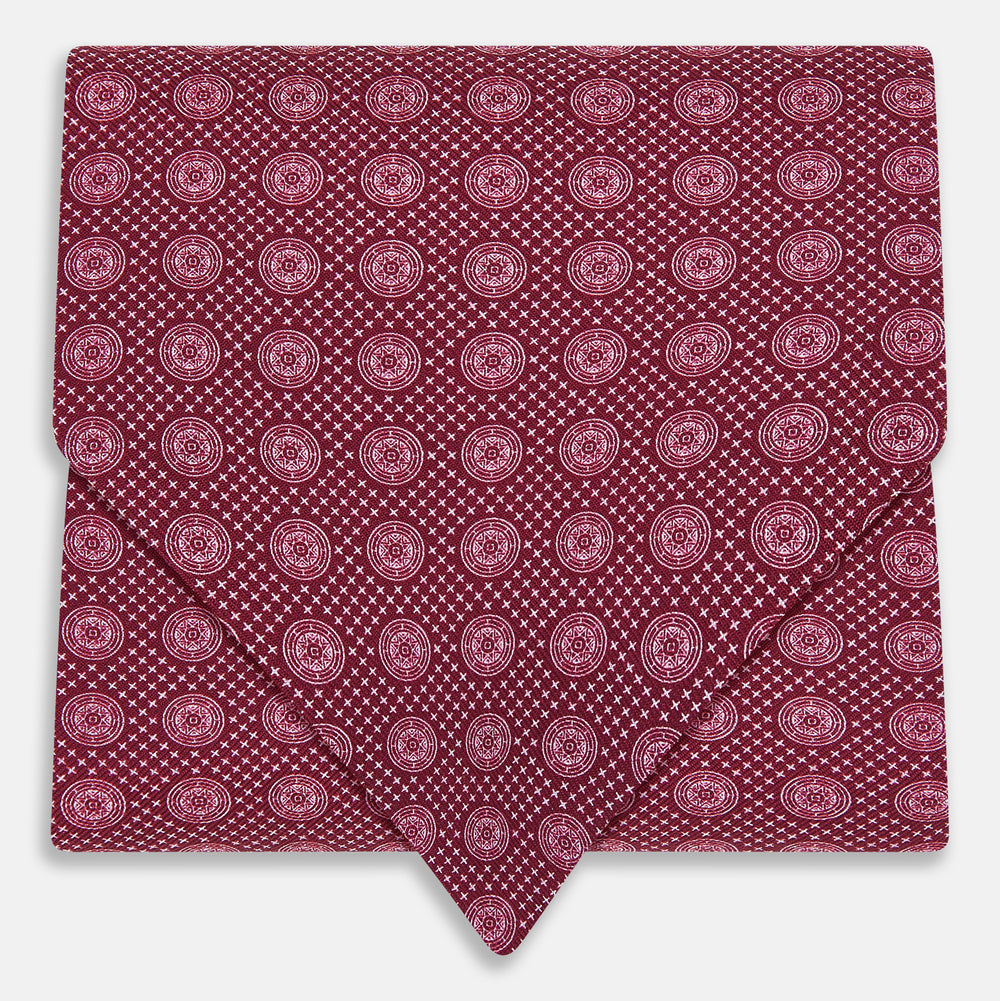 The Burgundy Medallion Silk Cravat by Turnbull & Asser features a white geometric medallion pattern, neatly crafted for an elegant accessory inspired by classic British style.