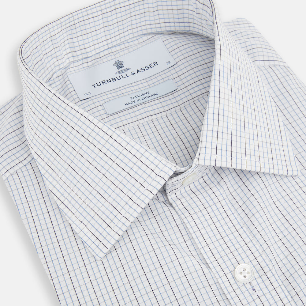 The Turnbull & Asser Pale Blue and Grey Grid Check Mayfair Shirt features long sleeves, a pointed collar, and buttoned cuffs. Crafted from Italian cotton, it displays a subtle grid pattern on a plain white background.