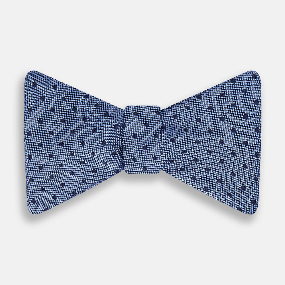The Turnbull & Asser Blue Micro Dot Silk Bow Tie features a subtle textured pattern with small navy polka dots, shown on a white background—an ideal accessory for smart attire.